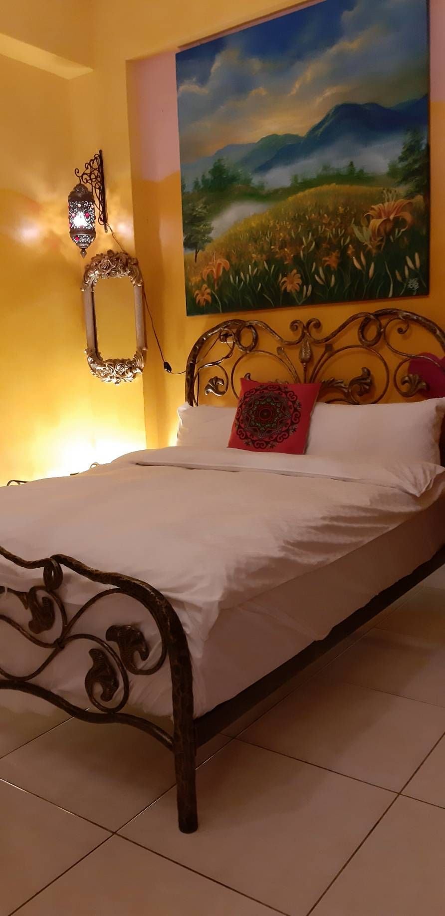 A bed with a metal frame, white bedding, and a decorative pillow.