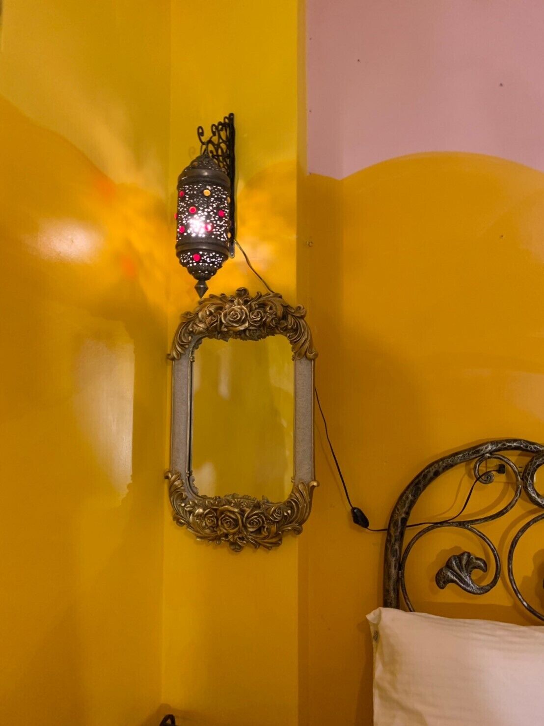 A yellow wall with a decorative mirror and a wall-mounted lantern.