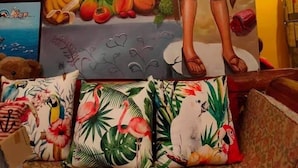 Una habitación con un amplio mural de una playa, almohadas tropicales y un cuadro enmarcado de un personaje de caricatura.