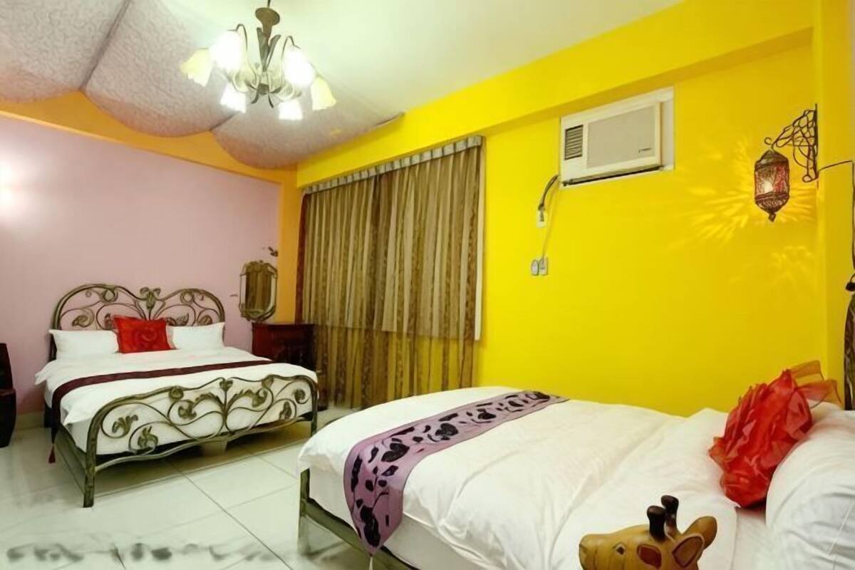 Una habitación con dos camas, una araña, un aire acondicionado y una lámpara de pared decorativa.
