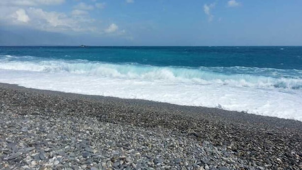 Una playa de guijarros con olas rompiendo en la orilla.