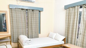 A hotel room with a single bed, a wooden nightstand, a desk with a chair, and a ceiling fan. - Hotel Mountain View (Pokhara)