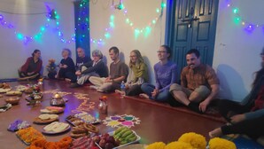A group of people seated on a floor, surrounded by various food items and decorations, indicating a social gathering or event. - Hotel Mountain View (Pokhara)