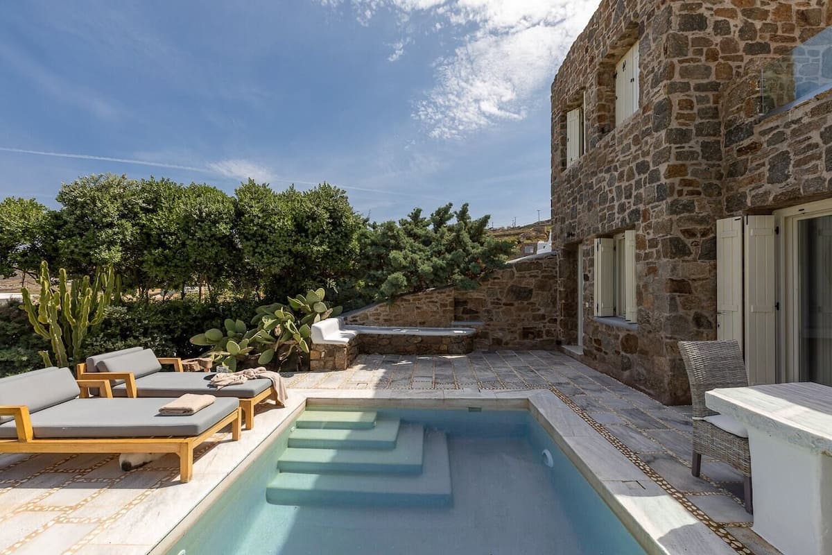 Un bâtiment en pierre doté d’une piscine, d’un espace extérieur aménagé et d’une végétation luxuriante.