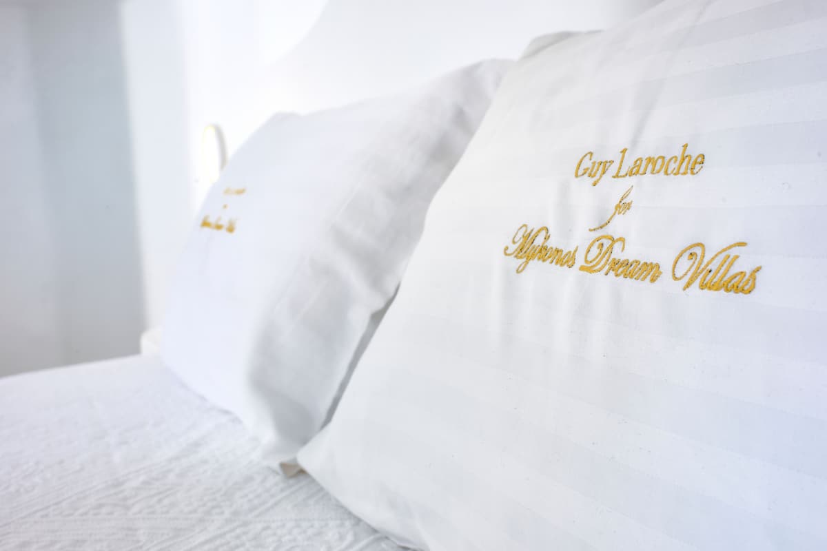 Un coussin blanc orné d'une broderie dorée formant un motif textuel.