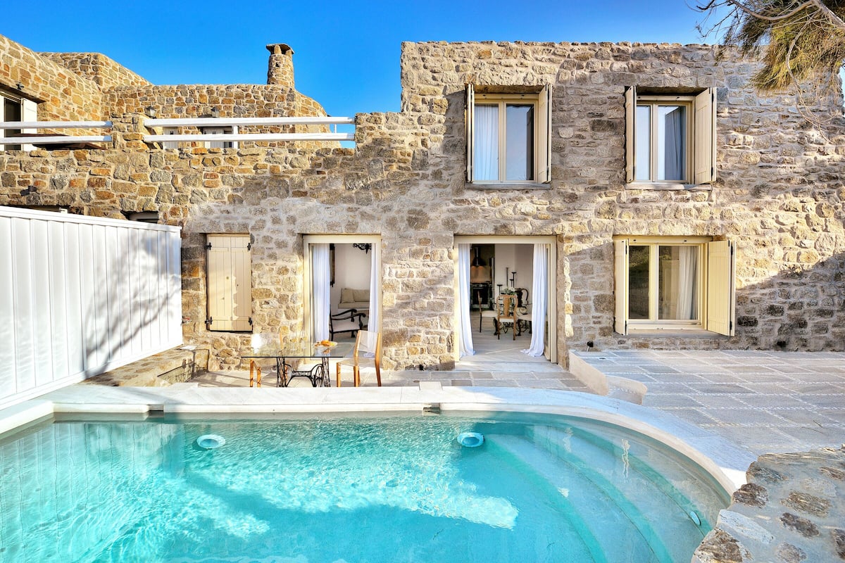 Un bâtiment en pierre doté d’une piscine, d’un espace extérieur aménagé et d’un escalier menant à un niveau supérieur.