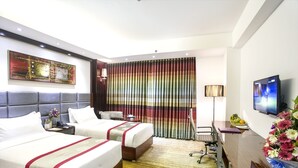 A hotel room with two beds, a desk, a TV, and a large window with curtains. - Hotel Bengal Blueberry (Dhaka)