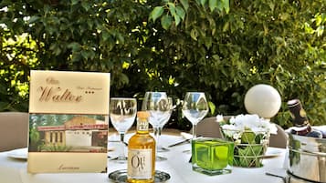 A table set outdoors with a bottle of olive oil, a menu, and glasses.