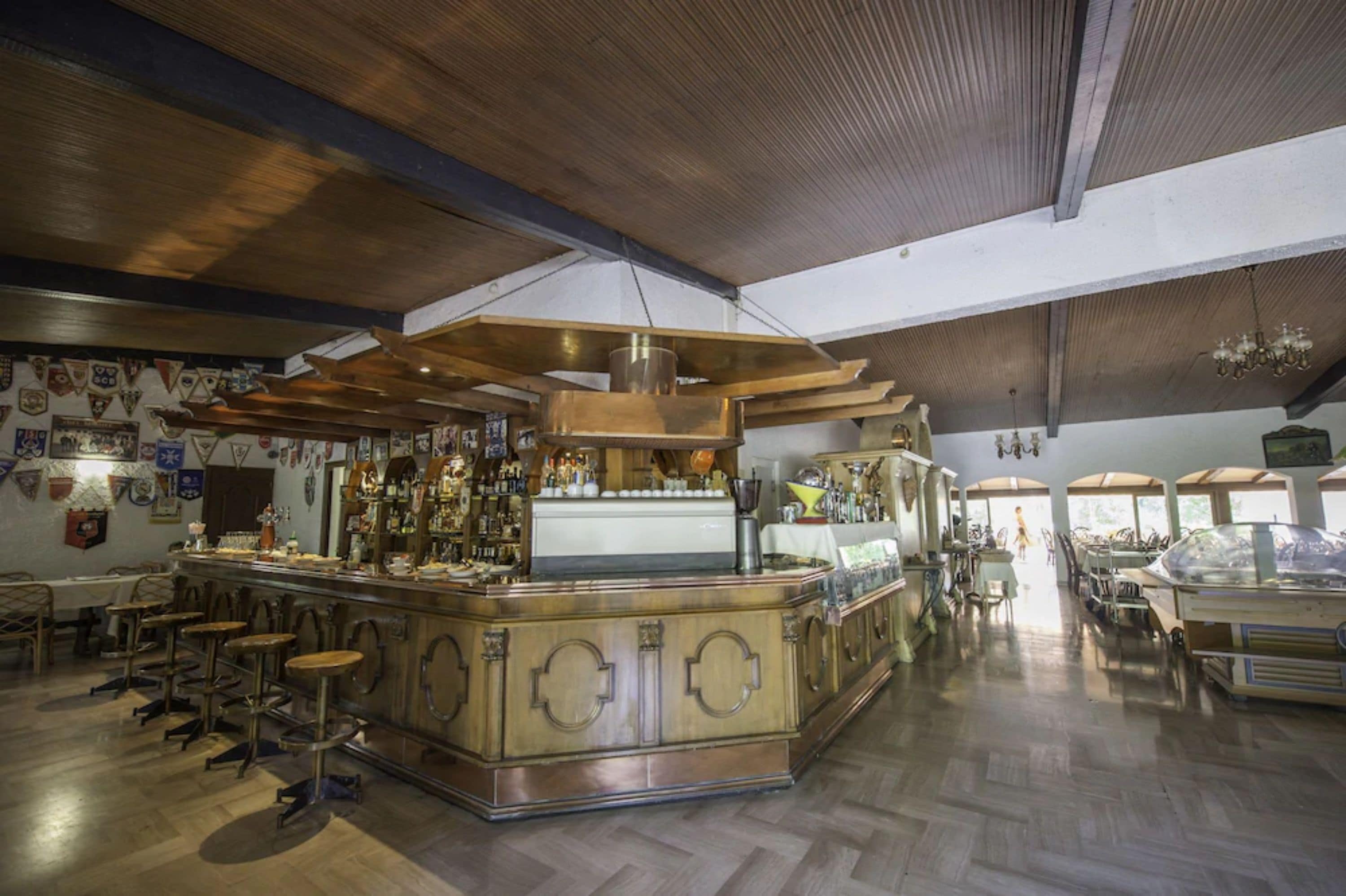 Eine Bar mit einer zentralen Bar, Hockstühlen und einer Auswahl an Flaschen und Gläsern.