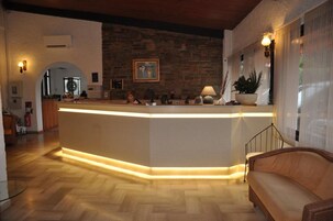 Un área de recepción con un mostrador de madera, una pared de piedra y un sofá.
