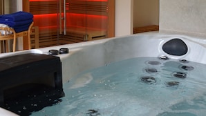 A spa room with a hot tub, wooden seating, and a sauna area. - Chez Walter (Lucciana)