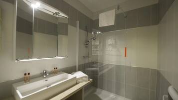 A modern bathroom with a large mirror, a sink, and a shower area.