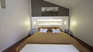 Ein modernes Hotelzimmer mit einem großen Bett, einer mit Beleuchtung versehenen Kopfteil, einem Gemälde an der Wand und Nachttischen mit Lampen.