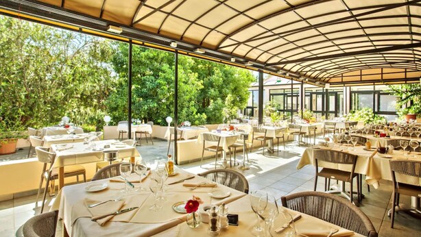 An outdoor dining area with tables set for a meal, surrounded by greenery and a covered patio. - Chez Walter (Lucciana)