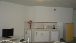 A small, clean room with a kitchenette, a bed, and a television.