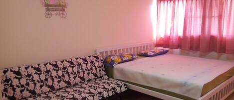 A bedroom with a bed, a sofa, and a wall decoration.