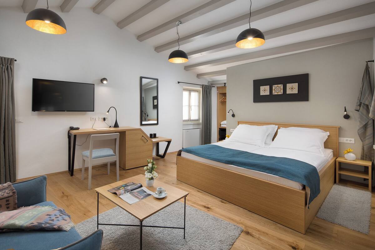 A modern bedroom with a wooden bed, a desk, and a television.
