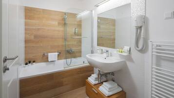 A modern bathroom with a wooden floor, a white bathtub, a sink, and a mirror.