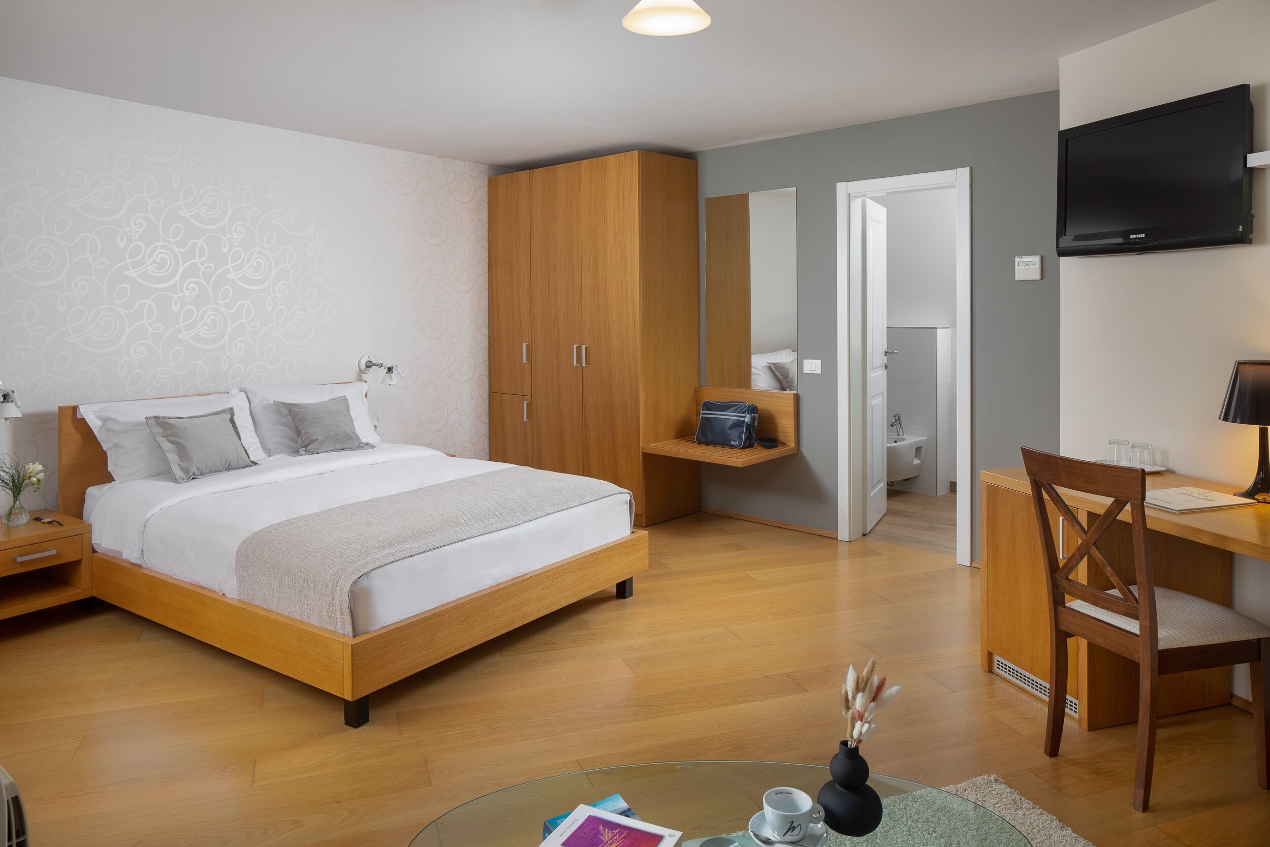 Un dormitorio moderno con una cama de madera, un escritorio, una silla y un televisor.