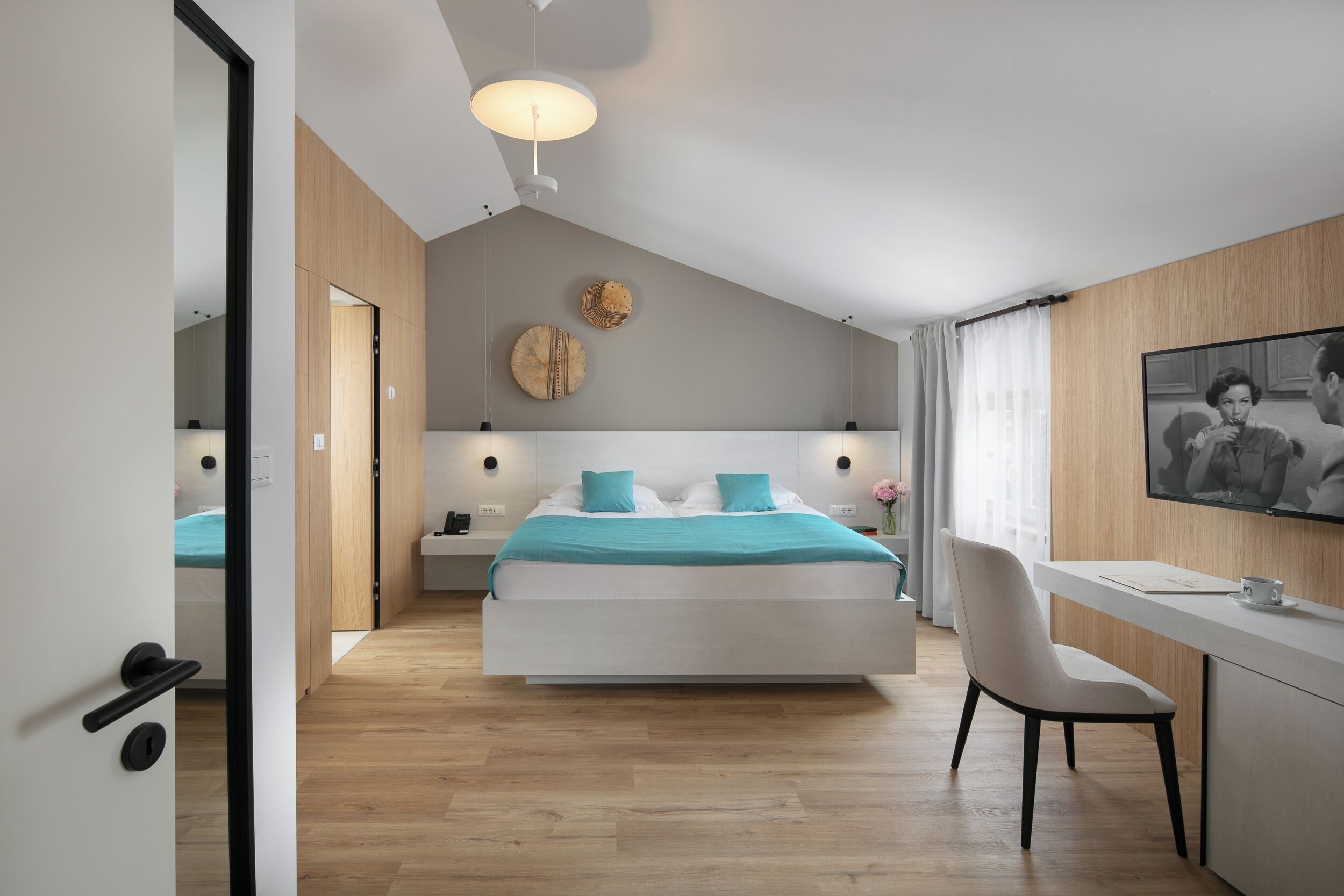 A modern bedroom with a bed, bedside tables, a desk, and a chair.