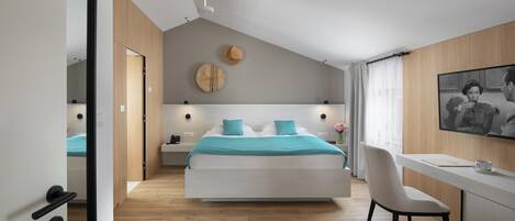 A modern bedroom with a bed, bedside tables, a desk, and a chair.