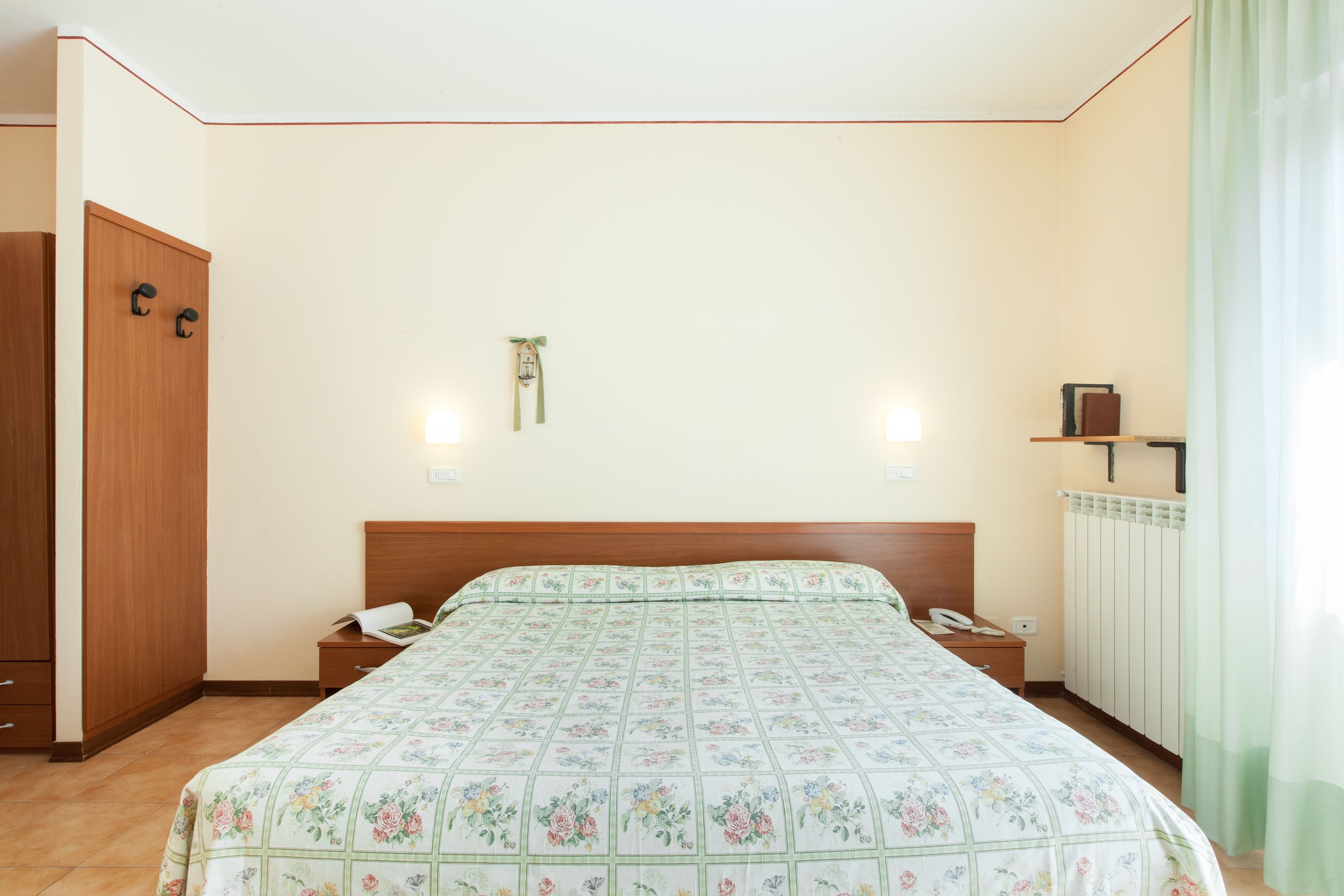 Une chambre à coucher comprenant un lit, des tables de chevet, une armoire et un radiateur.