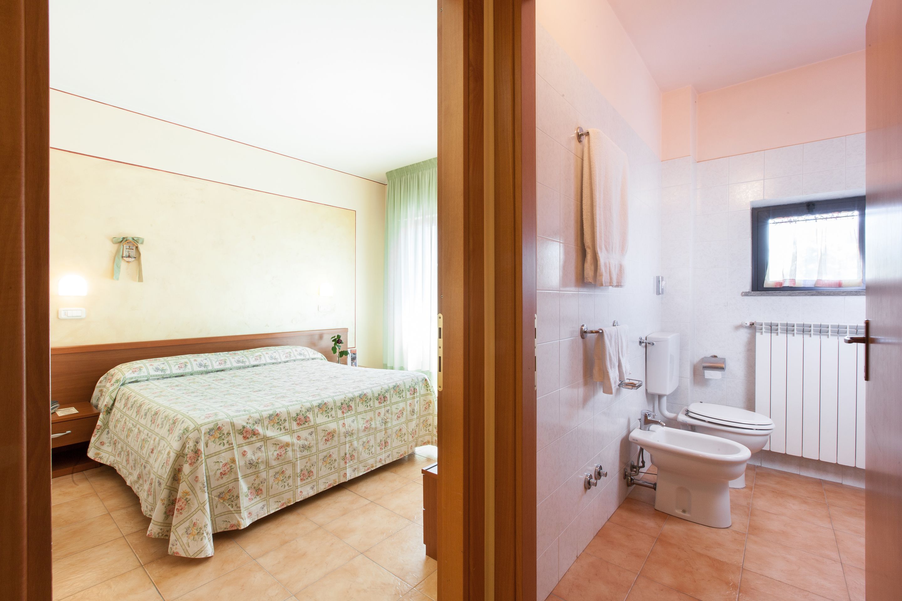 A bedroom with a bed and a bathroom with a toilet and bidet.
