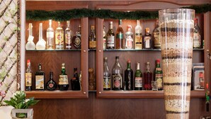 A bar area with shelves of liquor bottles and a large transparent container filled with layered materials.
