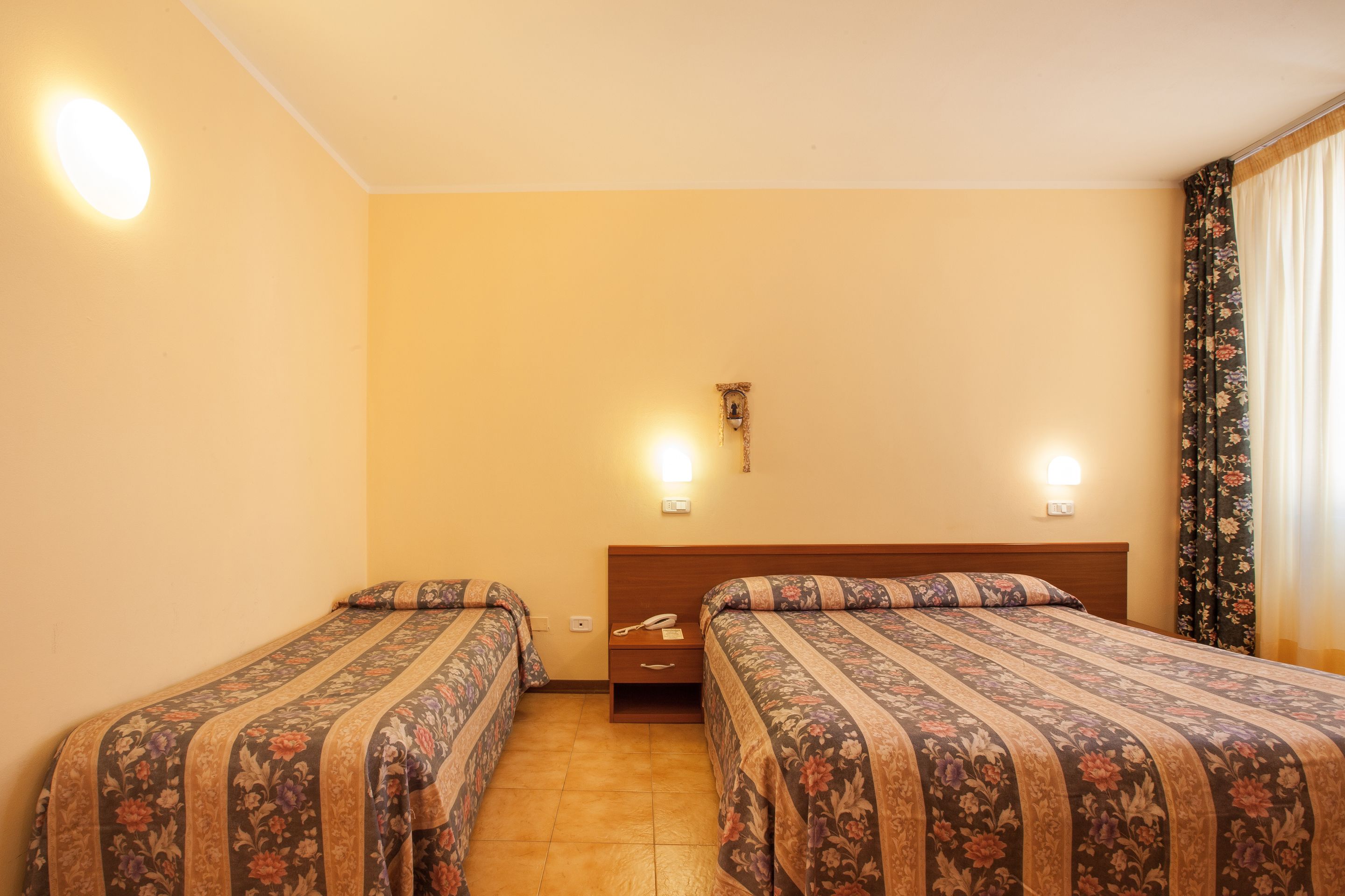 Une chambre d’hôtel avec deux lits, une table de chevet et un téléphone fixé au mur.