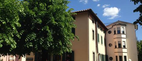 Un bâtiment avec une enseigne indiquant la présence d’un restaurant, des tables à l’extérieur et un arbre devant.