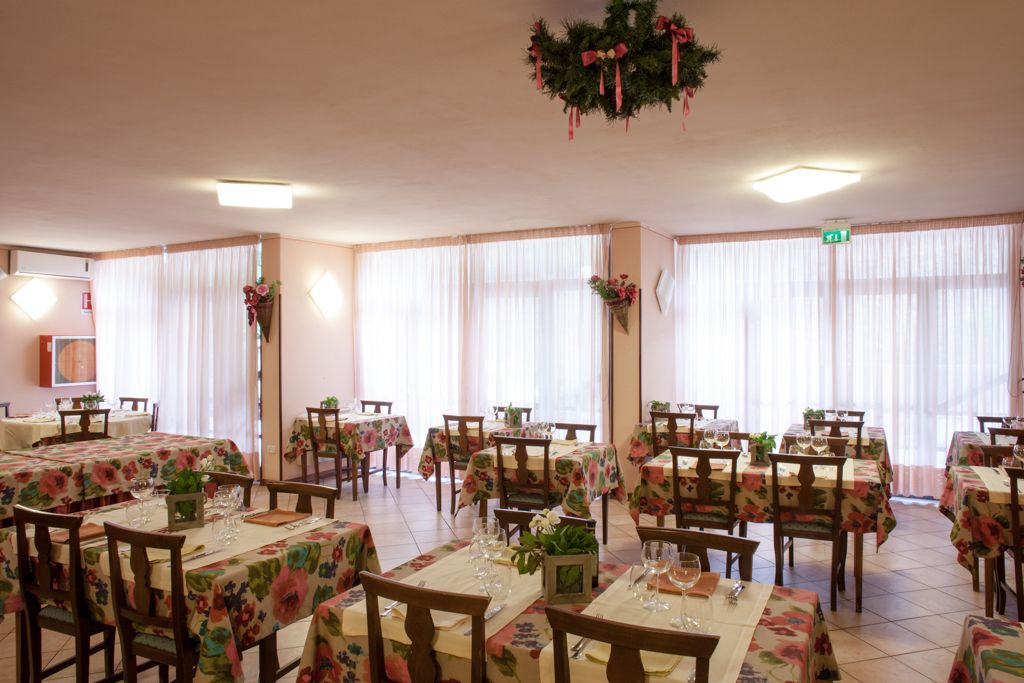 A dining area with multiple tables, each covered with floral tablecloths and set with wine glasses and cutlery.