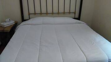 A neatly made bed with a white bedspread and a metal headboard with circular designs.