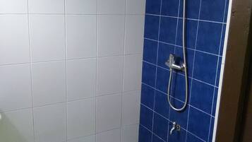 A bathroom with white and blue tiles, a shower, and a toilet.