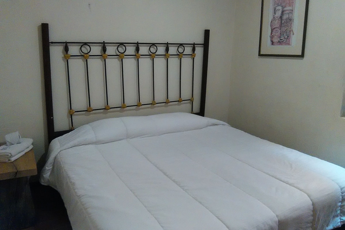 A bed with a metal headboard and a white bedspread.