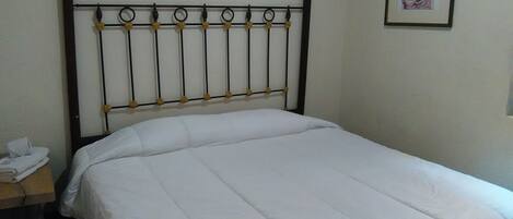 A bed with a metal headboard and a white bedspread.