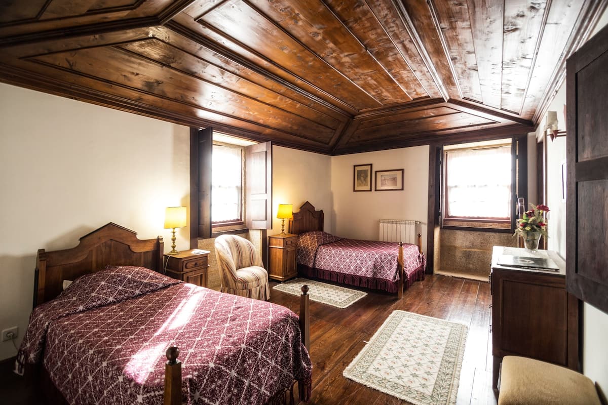 A room with two wooden beds, a chair, a desk, and a radiator.