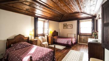 Una habitación con dos camas de madera, una silla, un escritorio y un radiador.