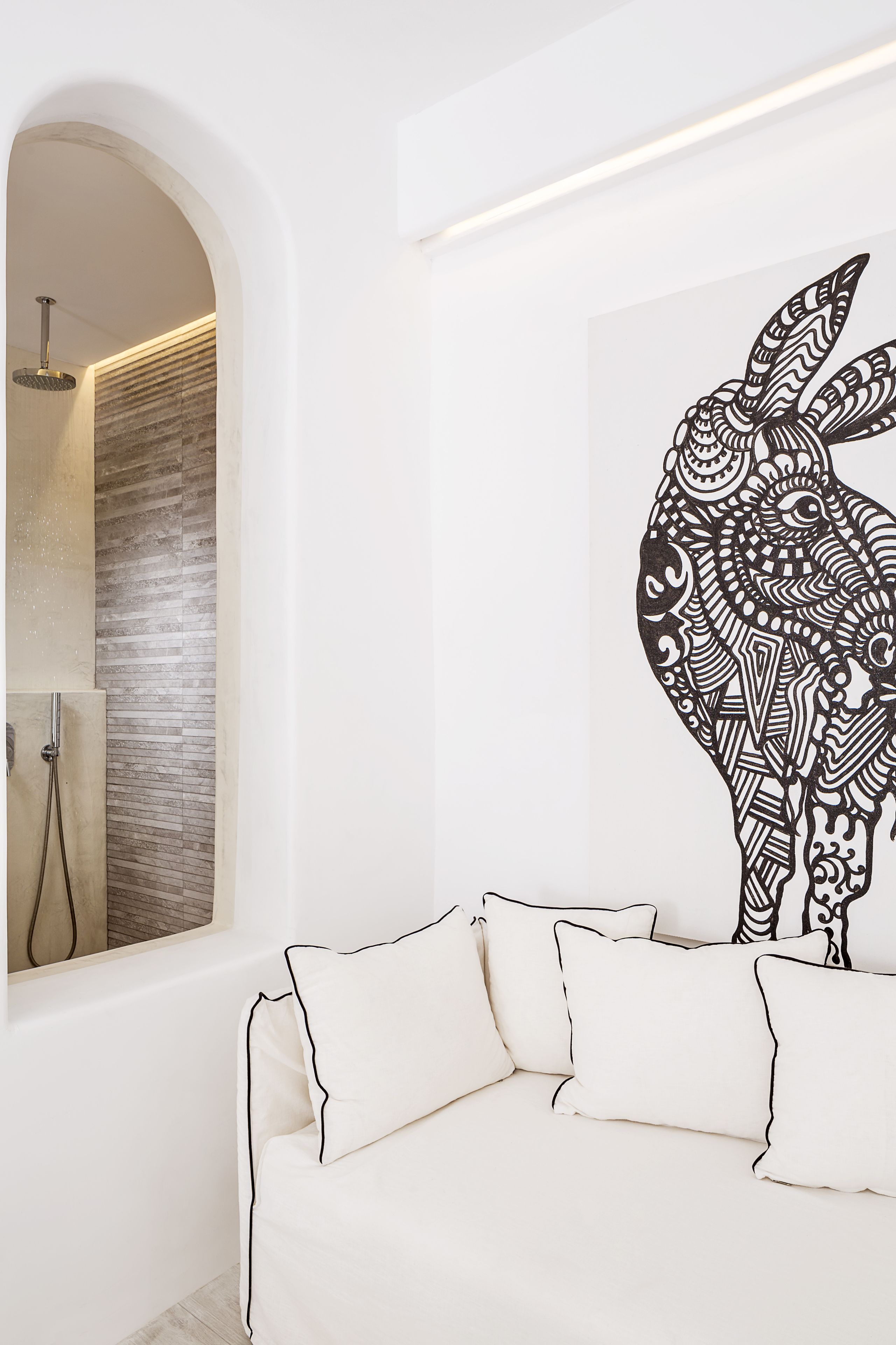 Un intérieur moderne avec un canapé blanc, un mur décoré d’un motif et un espace douche.
