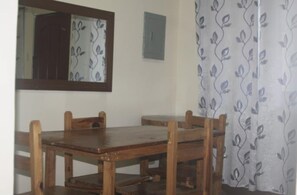 A wooden dining table with four chairs, a mirror, and a patterned curtain. - Albergo Hotel (Baguio)