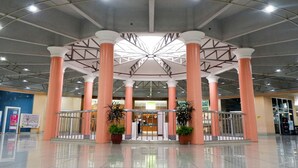 A spacious lobby with a central atrium, large columns, and potted plants. - Albergo Hotel (Baguio)
