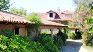 A rustic building with a tiled roof, surrounded by lush greenery and a cobblestone path. - Quinta da Roseira (Ponte de Lima)