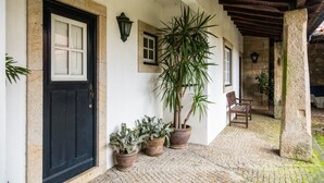 A stone building with a black door, potted plants, and a wooden bench. - Quinta da Roseira (Ponte de Lima)