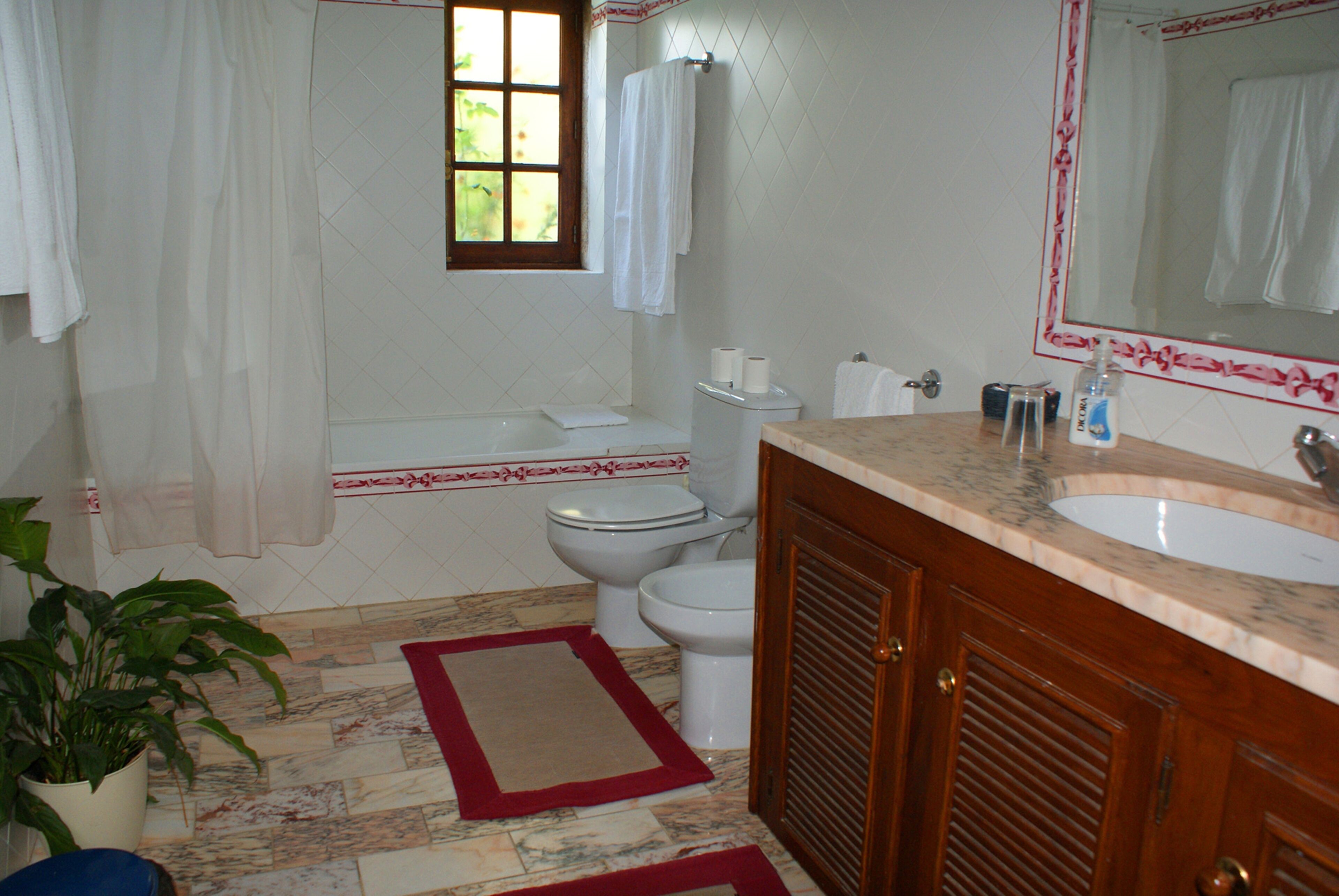 Une salle de bain équipée d’une baignoire, de toilettes, d’un lavabo et d’un miroir.