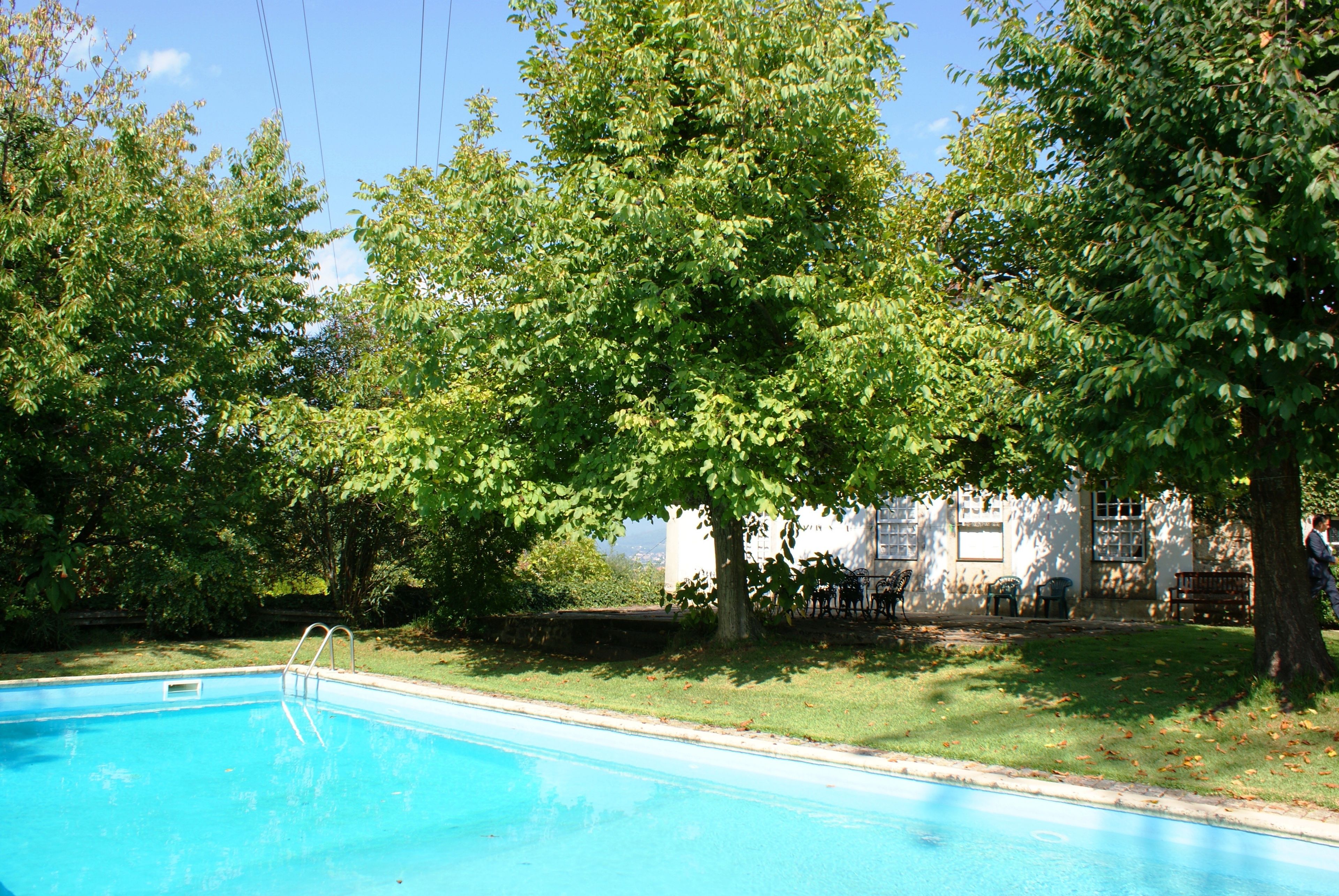 Ein Pool, umgeben von Bäumen und einem Gebäude mit weißer Fassade.