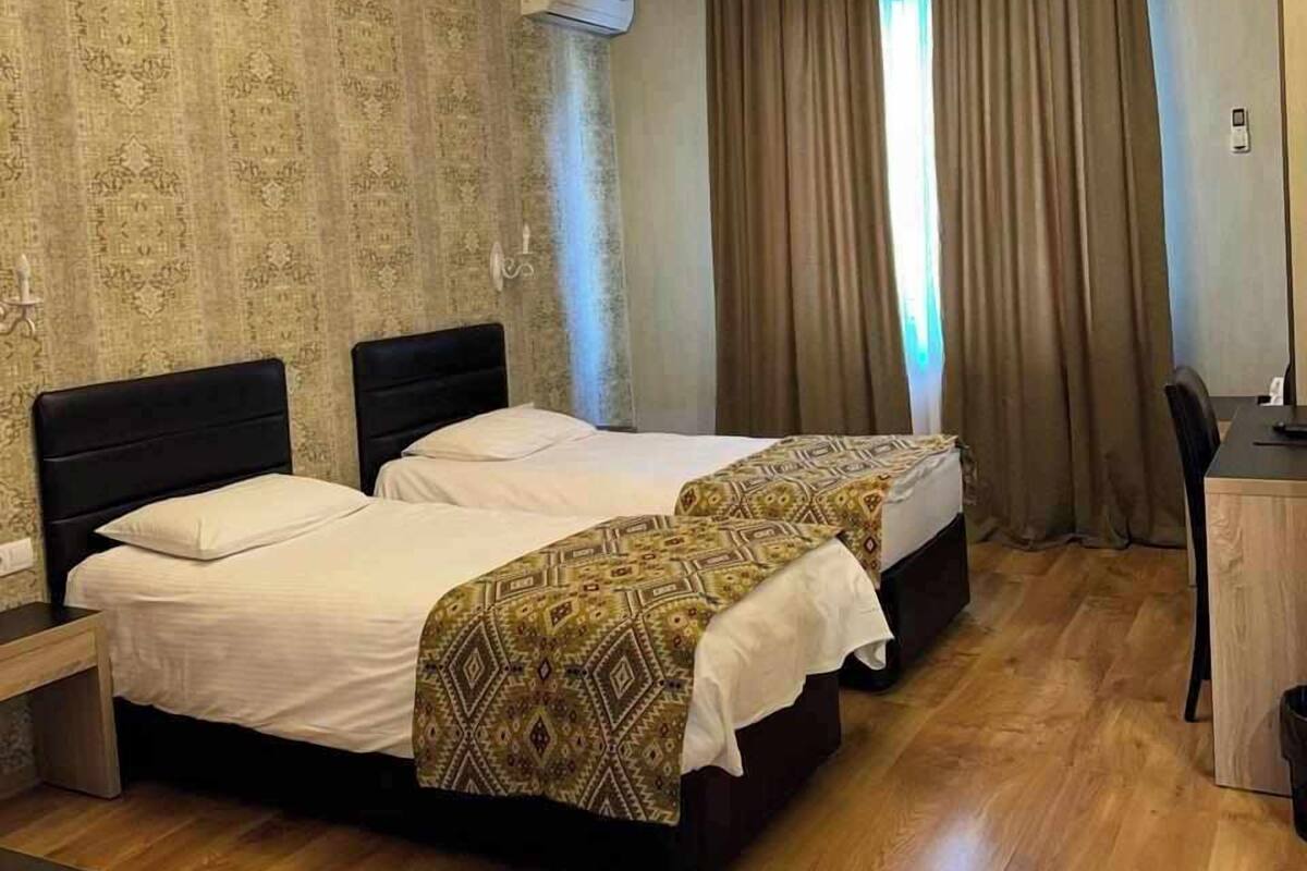 Habitación de hotel con dos camas, una araña, un equipo de aire acondicionado y un escritorio.
