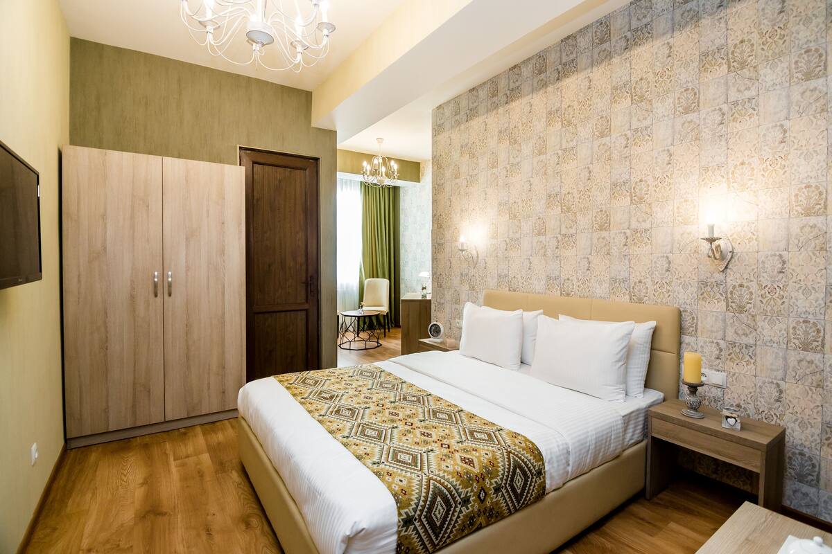 Una habitación de hotel con cama, armario, mesita de noche con lámpara y candelabro.