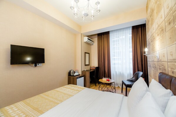 Une chambre d’hôtel équipée d’un lit, d’un bureau, d’une chaise, d’une télévision et d’un appareil de climatisation.