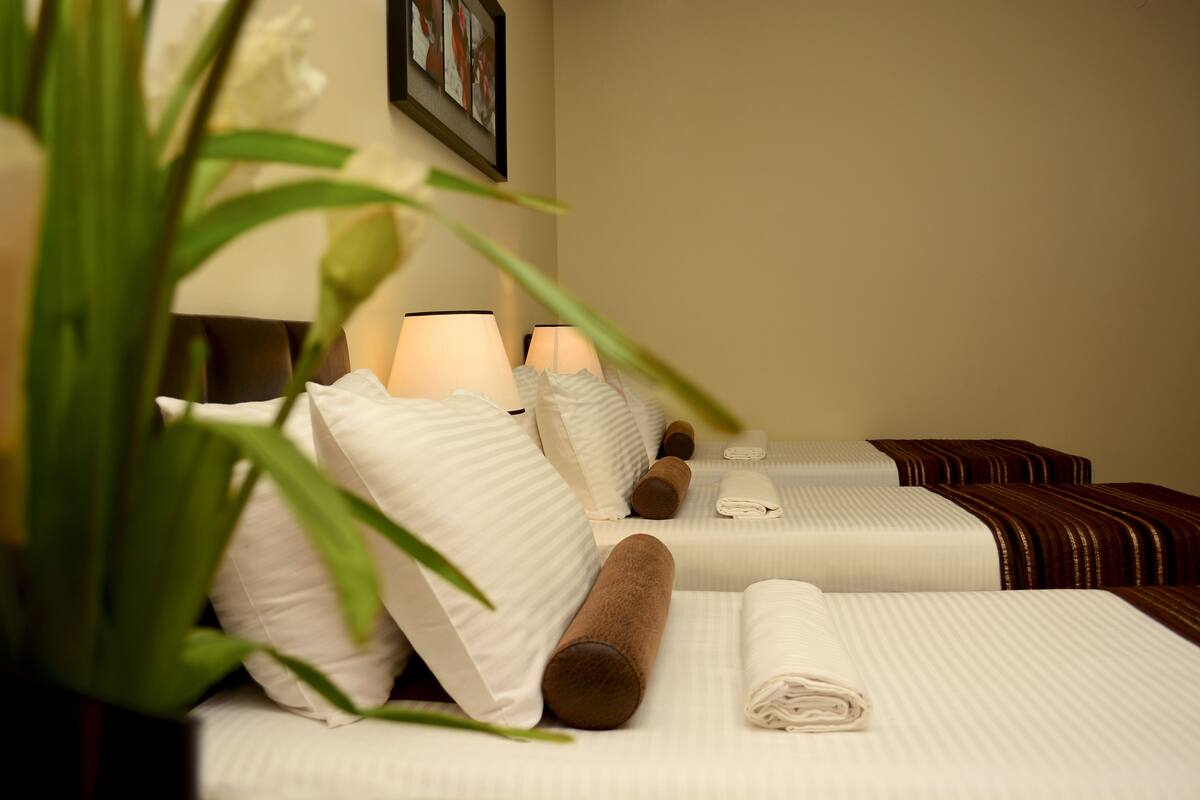 Una habitación de hotel con camas bien hechas, ropa de cama blanca y toallas marrones.