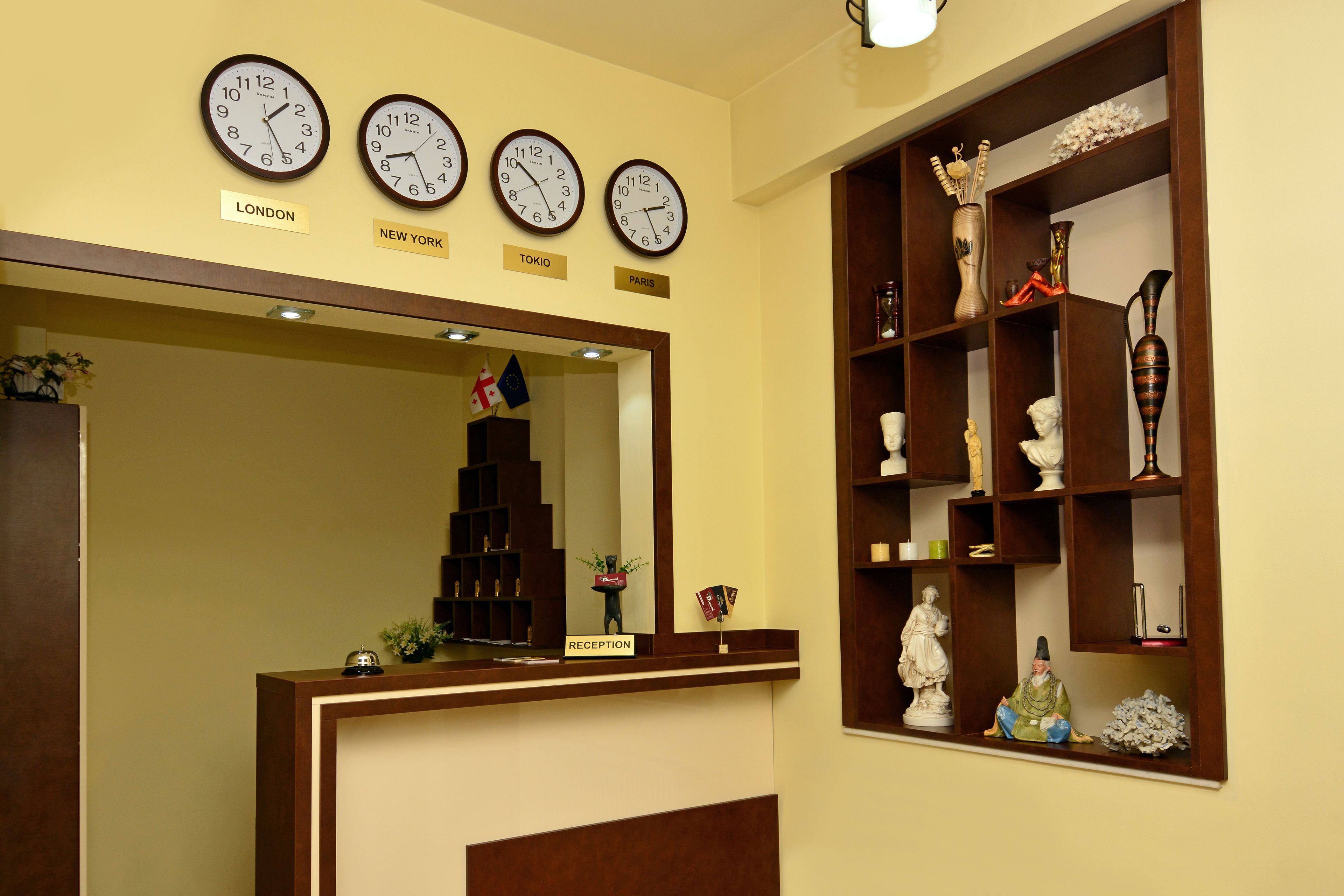A reception area with clocks labeled London, New York, Tokyo, and Paris. There are shelves with decorative items and a reception desk.