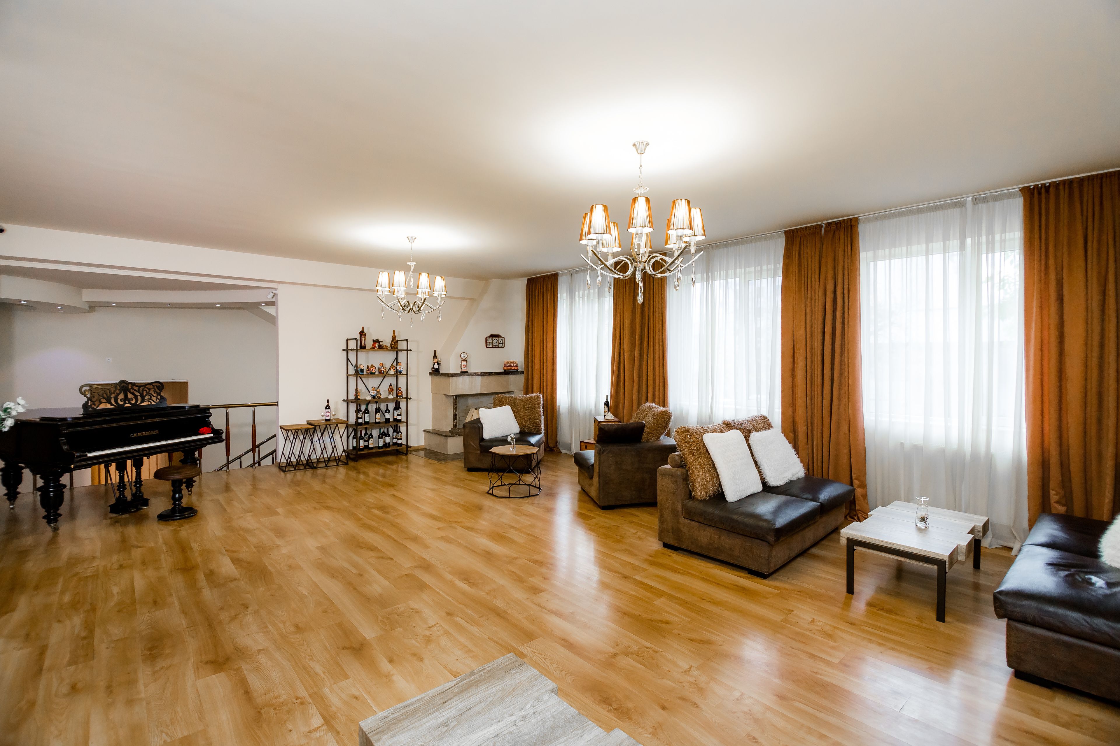 A spacious living room with a grand piano, sofas, a coffee table, and a chandelier.